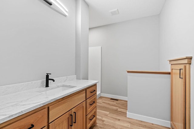 bathroom with visible vents, vanity, baseboards, and wood finished floors