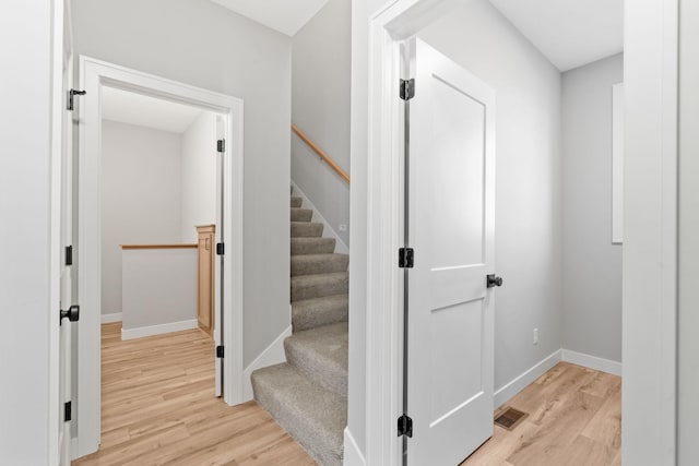 stairs with visible vents, wood finished floors, and baseboards