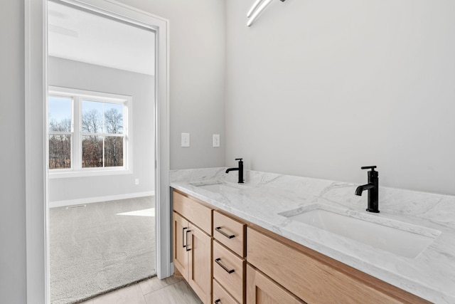 bathroom featuring double vanity, baseboards, and a sink