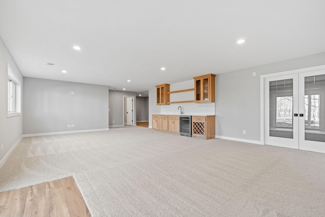 unfurnished living room with light carpet, beverage cooler, recessed lighting, french doors, and wet bar