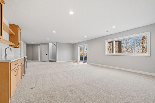 unfurnished living room with a sink, stairway, light carpet, and recessed lighting