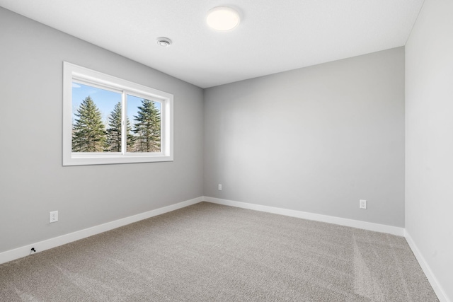 carpeted empty room featuring baseboards