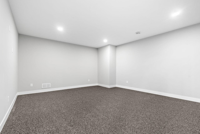 empty room featuring dark colored carpet, visible vents, baseboards, and recessed lighting