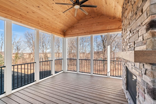 unfurnished sunroom featuring a wealth of natural light, lofted ceiling, an outdoor stone fireplace, and wooden ceiling