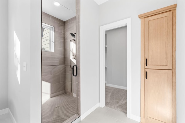 bathroom featuring tile patterned flooring, a shower stall, and baseboards