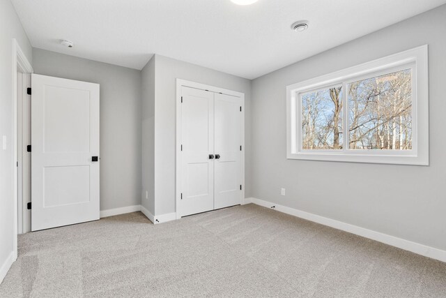 unfurnished bedroom with baseboards, carpet floors, and a closet