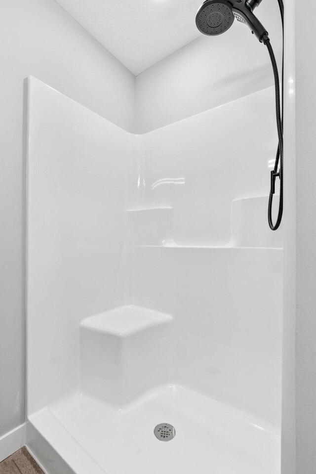 bathroom with a shower and baseboards