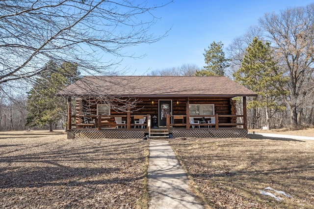 view of front of house featuring a porch, log siding, and a shingled roof