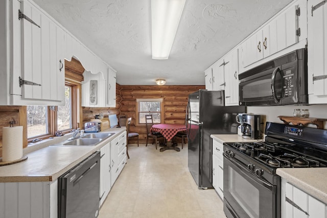 kitchen with a sink, black appliances, light countertops, a textured ceiling, and white cabinetry