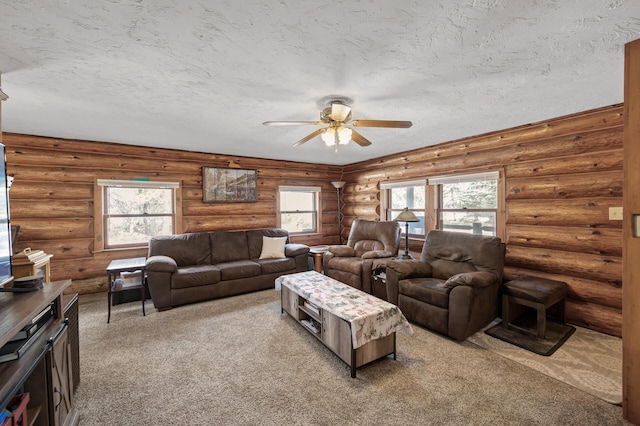 living area with ceiling fan, rustic walls, carpet, and a textured ceiling