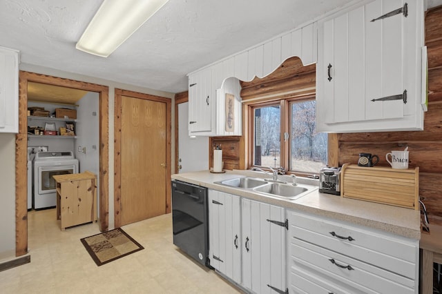 kitchen with a sink, black dishwasher, white cabinets, light floors, and washer / dryer