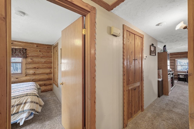 hall featuring log walls, a textured ceiling, and carpet flooring