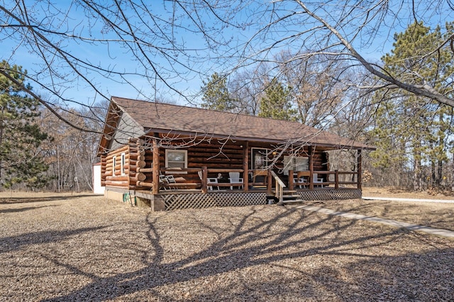 cabin with log siding, a porch, and a shingled roof