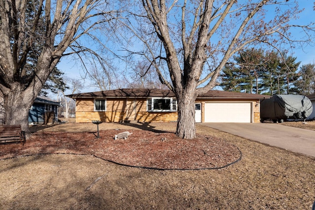 single story home with concrete driveway, an attached garage, and brick siding