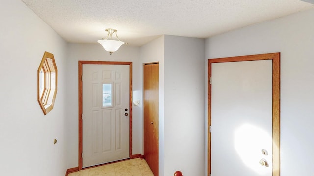 entryway with light floors and a textured ceiling