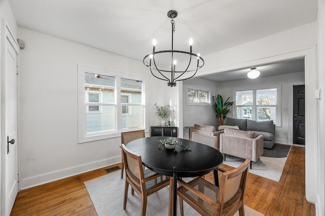 dining area featuring hardwood / wood-style floors, baseboards, visible vents, and a chandelier