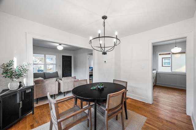 dining area featuring baseboards, a notable chandelier, a healthy amount of sunlight, and wood finished floors