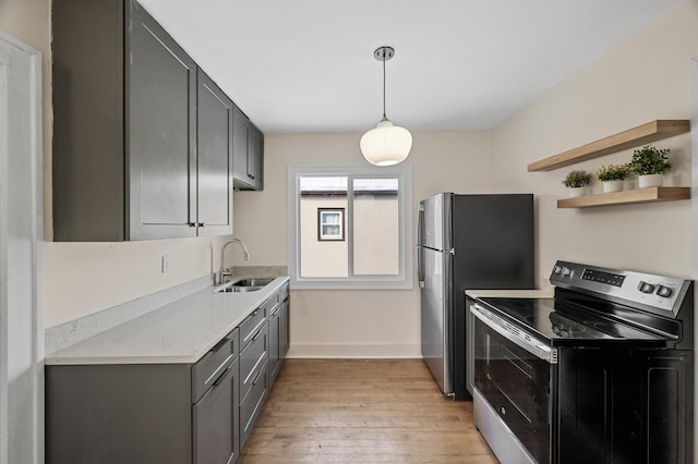 kitchen with baseboards, electric stove, light wood-style floors, hanging light fixtures, and a sink