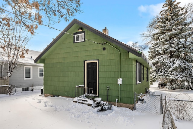 snow covered rear of property with a chimney and fence