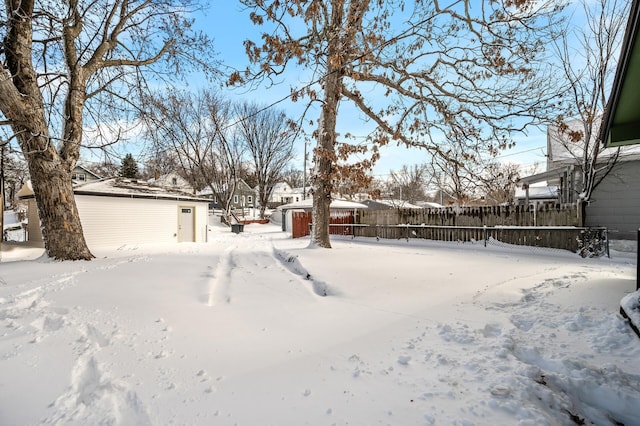 yard covered in snow with an outdoor structure and fence