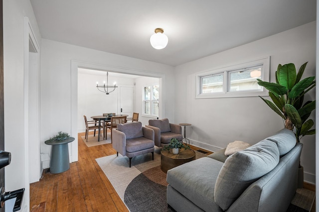 living area featuring baseboards, an inviting chandelier, and hardwood / wood-style floors