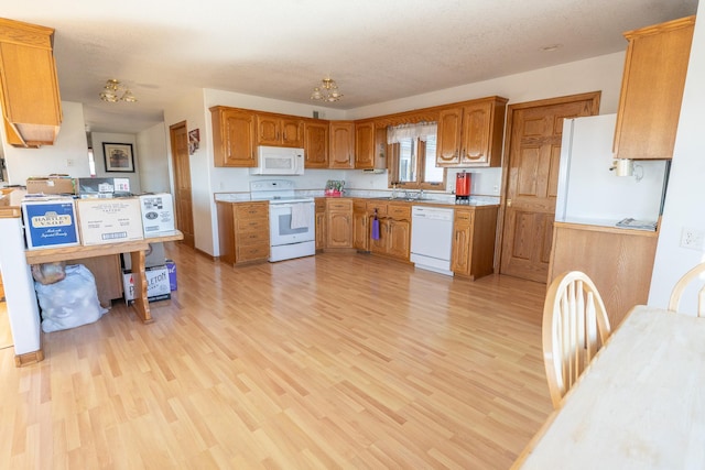 kitchen featuring brown cabinets, white appliances, an inviting chandelier, light wood finished floors, and light countertops