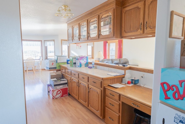 kitchen featuring light countertops, glass insert cabinets, light wood finished floors, and a chandelier