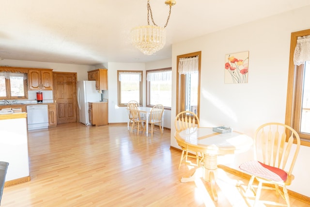 dining space featuring baseboards, light wood-style floors, and an inviting chandelier