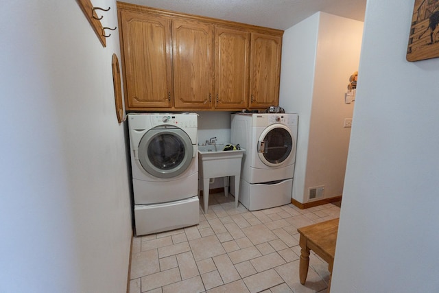 laundry area featuring visible vents, cabinet space, baseboards, and washing machine and dryer