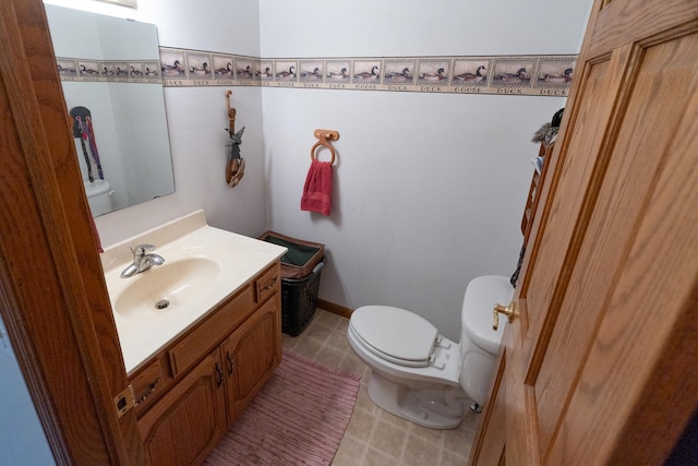 half bathroom featuring tile patterned floors, toilet, vanity, and baseboards