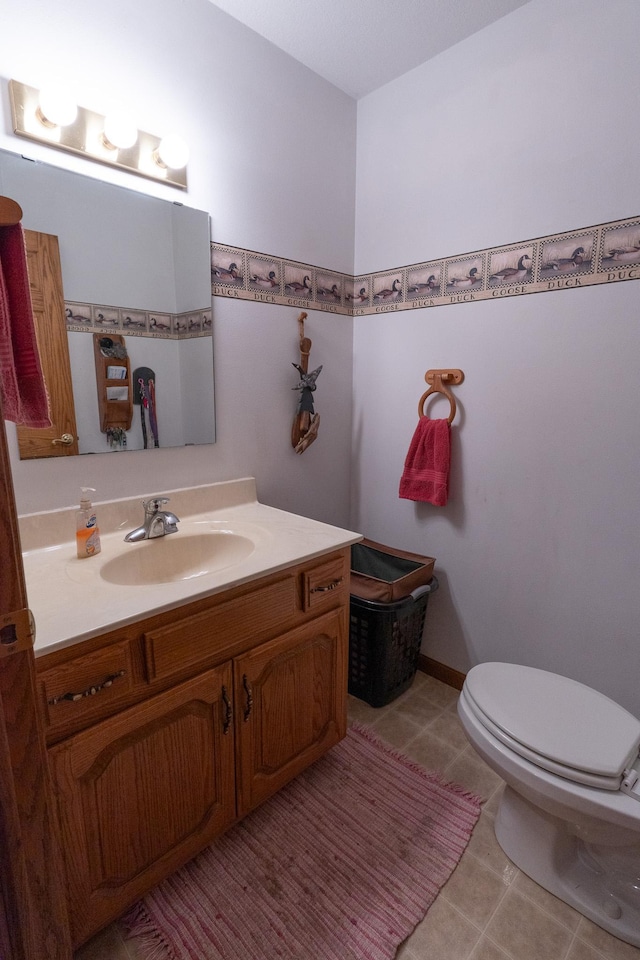 half bath with tile patterned floors, toilet, and vanity