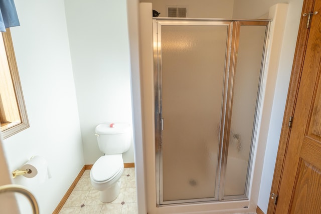 bathroom featuring tile patterned floors, a stall shower, toilet, and baseboards