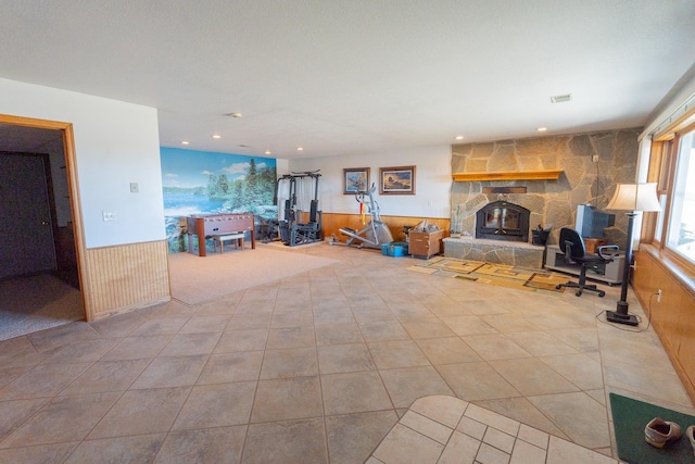 tiled living room featuring a wood stove, recessed lighting, a wainscoted wall, and wood walls