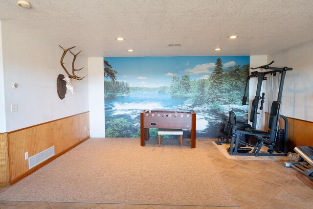 interior space with visible vents, a textured ceiling, a wainscoted wall, and wood walls