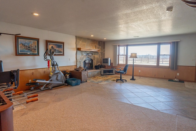 exercise room with tile patterned floors, a wainscoted wall, wood walls, and a textured ceiling