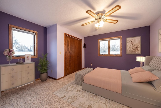 bedroom with a textured ceiling, a closet, carpet, baseboards, and ceiling fan