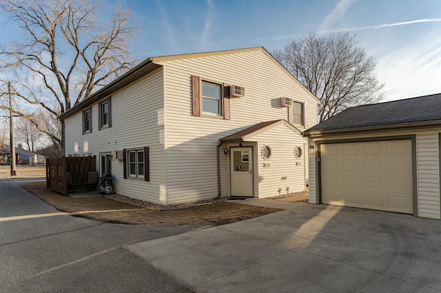 view of front facade with an AC wall unit, concrete driveway, and an attached garage