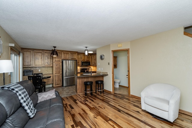 living area with baseboards, light wood-type flooring, and a textured ceiling