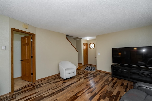 living room with a textured ceiling, baseboards, and wood finished floors