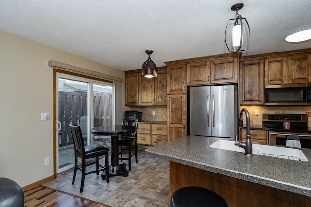 kitchen with dark countertops, hanging light fixtures, backsplash, and stainless steel appliances