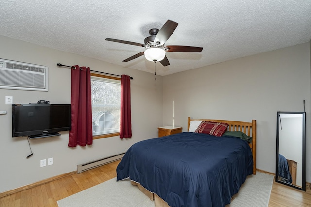 bedroom with a wall mounted AC, a textured ceiling, a baseboard heating unit, and wood finished floors