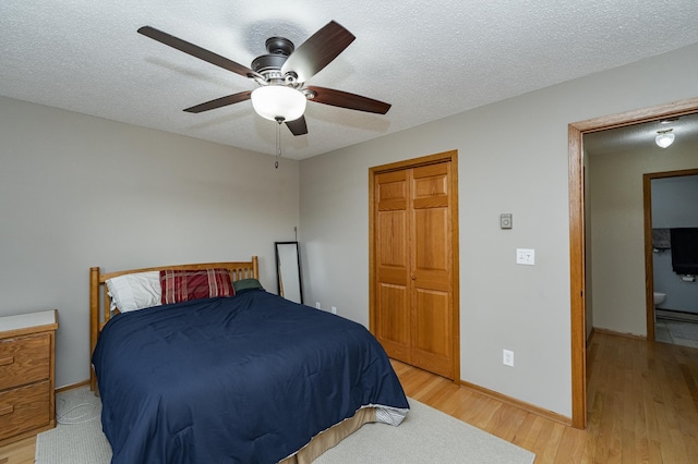 bedroom with baseboards, light wood finished floors, and a textured ceiling