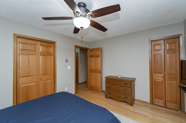 bedroom with baseboards, a textured ceiling, light wood-style floors, and a ceiling fan