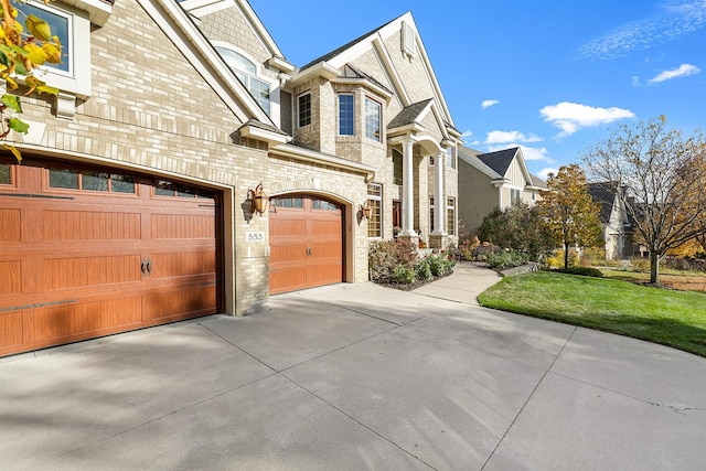 view of side of property with a garage, brick siding, concrete driveway, and a yard