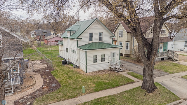 view of front of home featuring a front lawn, central AC unit, metal roof, entry steps, and fence