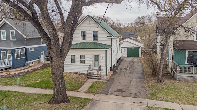 view of front of property with a front yard, an outbuilding, metal roof, driveway, and entry steps