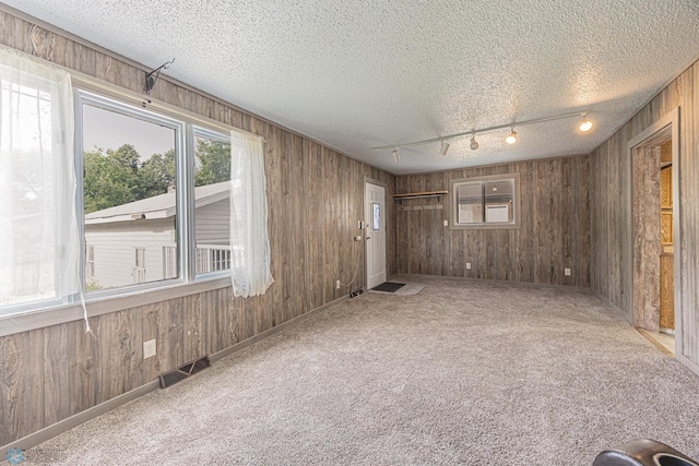1524 1st Ave S, Fargo, ND 58103 - empty room with rail lighting, wood walls, carpet flooring, and a textured ceiling