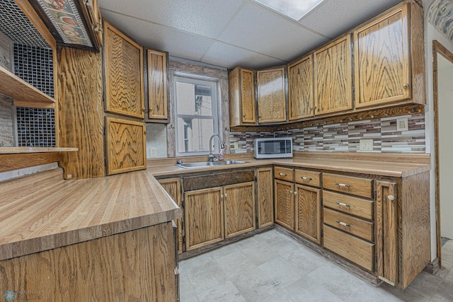 1524 1st Ave S, Fargo, ND 58103 - kitchen with a sink, stainless steel microwave, open shelves, decorative backsplash, and brown cabinetry