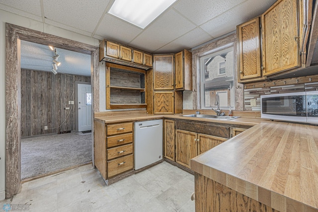 1524 1st Ave S, Fargo, ND 58103 - kitchen with white appliances, a sink, brown cabinetry, wood walls, and a paneled ceiling