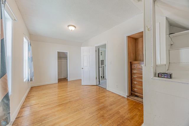 1524 1st Ave S, Fargo, ND 58103 - unfurnished bedroom featuring light wood finished floors, a spacious closet, a closet, baseboards, and a textured ceiling
